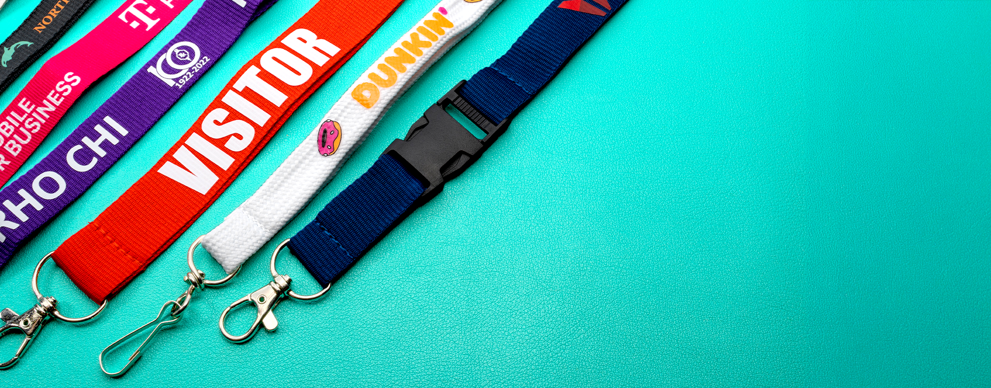 Colorful custom lanyards including Visitor, Dunkin, T-Mobile, and Rho Chi designs with various attachments
