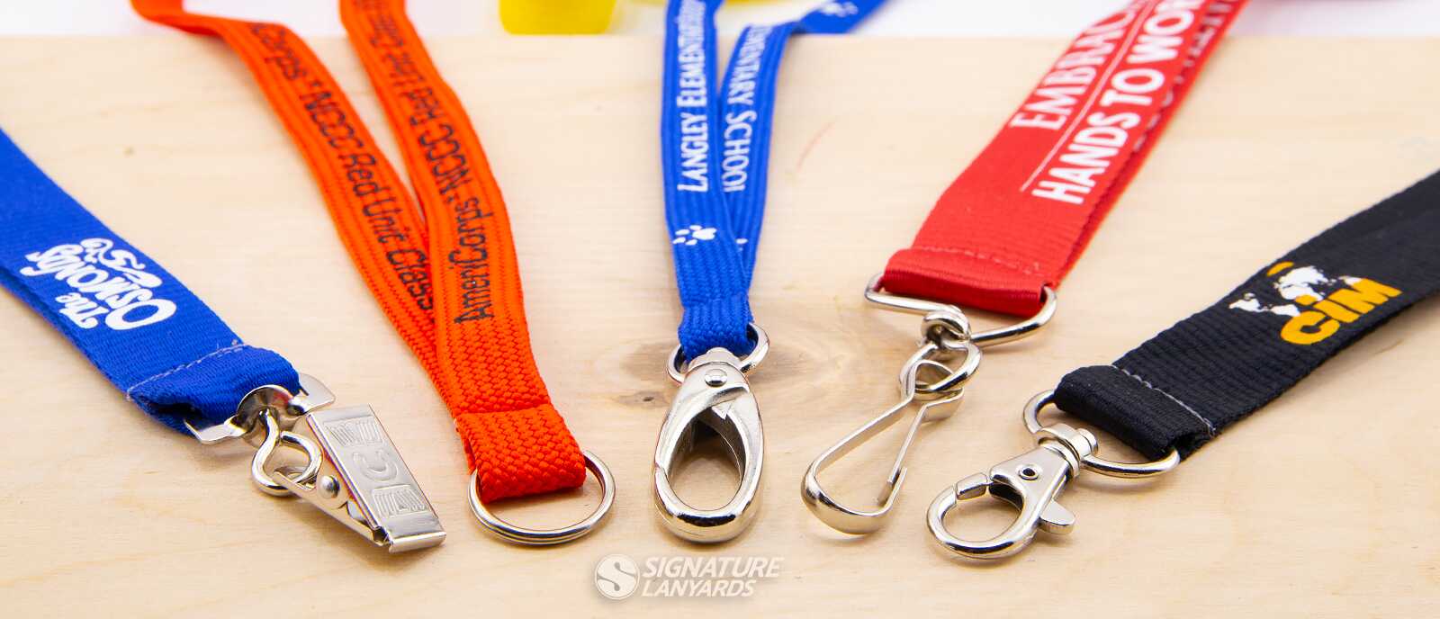 Five custom lanyards with lobster claw attachments featuring AmeriCorps, Langley School, Hands to Work, and CIM logos